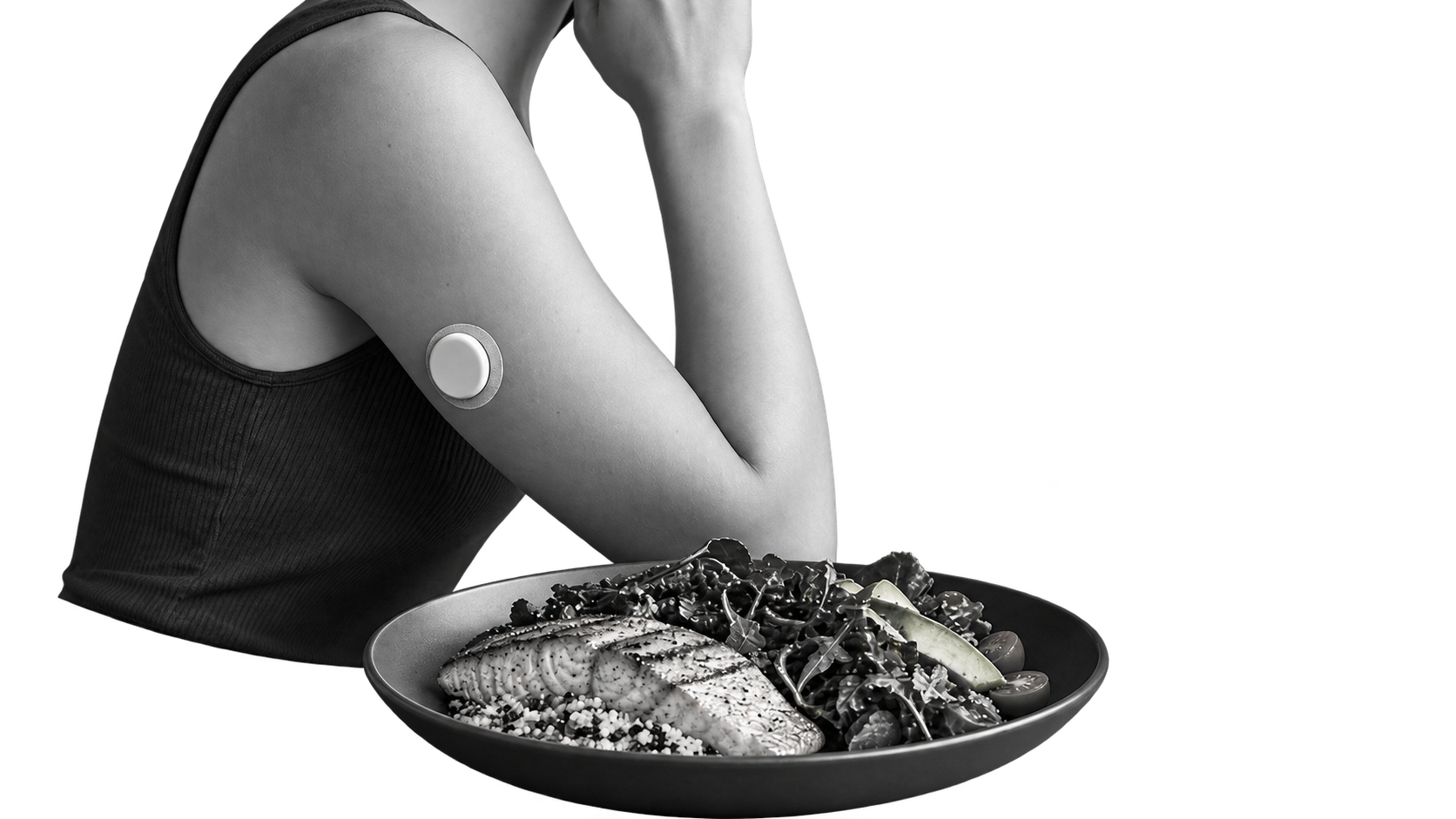 Persona con un sensor continuo de glucosa en el brazo junto a un plato de pescado y verduras.